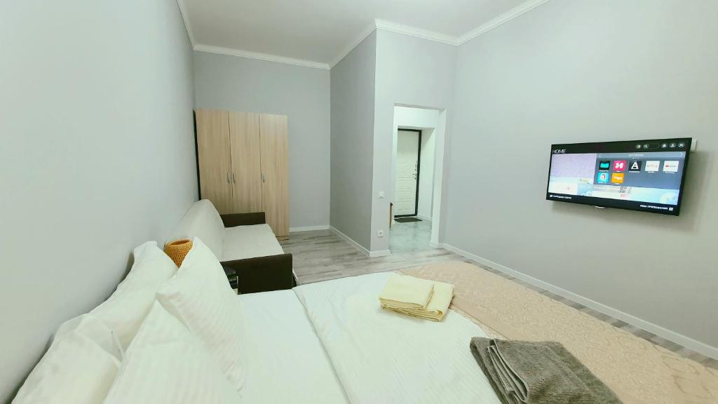 a white room with a bed and a flat screen tv at Luxembourg in Taldykolʼ