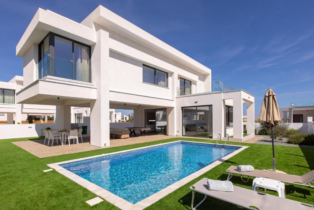 a villa with a swimming pool in front of a house at Nelia Panorama Villa in Protaras