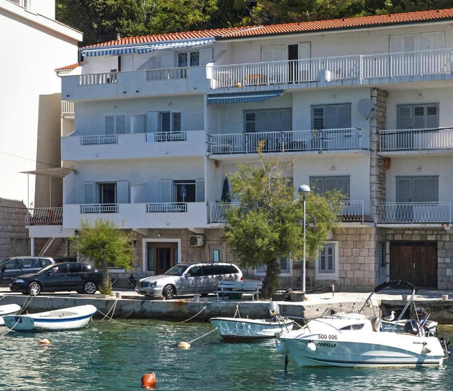 ein großes weißes Gebäude mit Booten im Wasser in der Unterkunft Apartments Ljiljana in Mimice