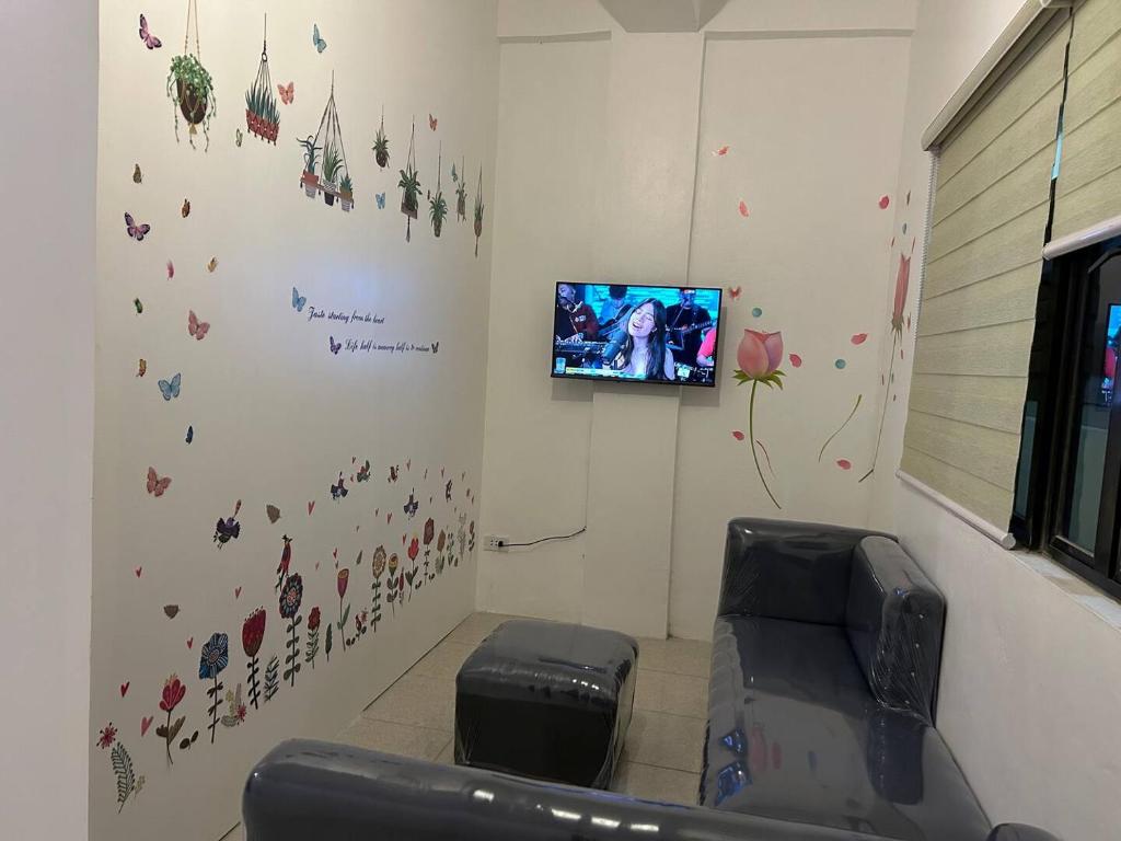 a living room with a tv on a wall with butterflies at Caishen Modern Affordable Apartelle 202 in Silang