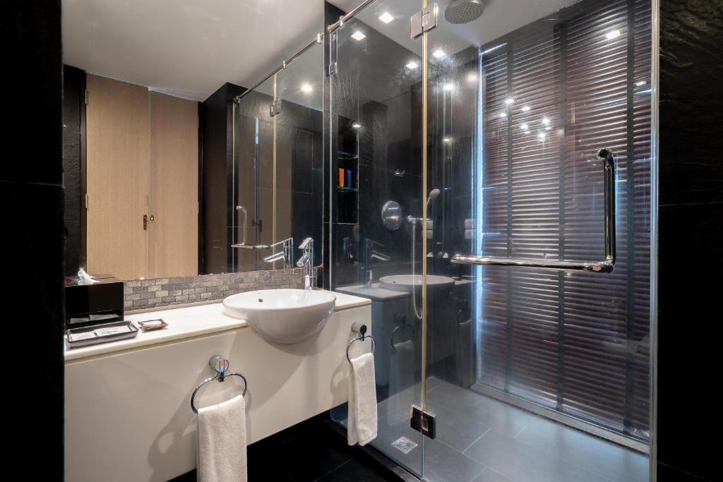 A compact bathroom pairs a vessel sink with a glass-enclosed rainfall shower.