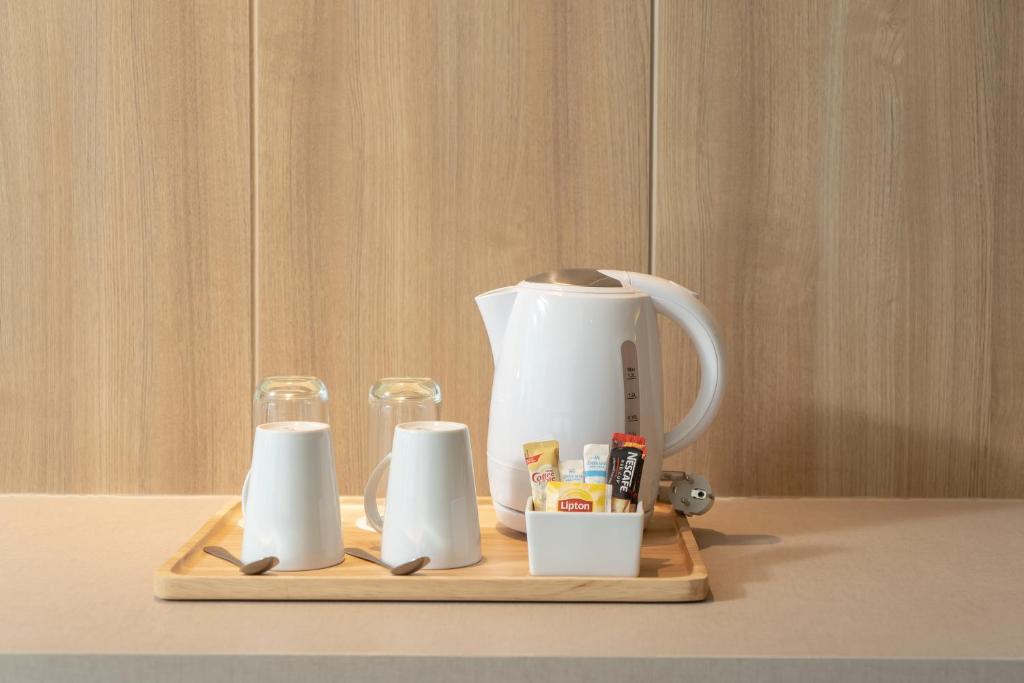 A tea and coffee station arranged on a wooden tray against built-in cabinetry.