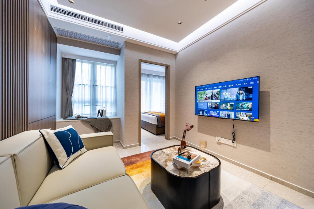 Una sala de estar con un sofá y un televisor en una pared. en 岗厦汇花园行政公寓酒店-深圳福田会展中心岗厦地铁站店, en Shenzhen