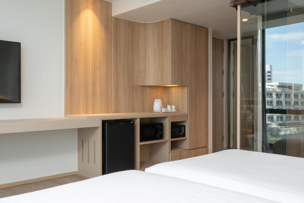 A bright bedroom includes a white bed, built-in storage and a glazed city-facing wall.