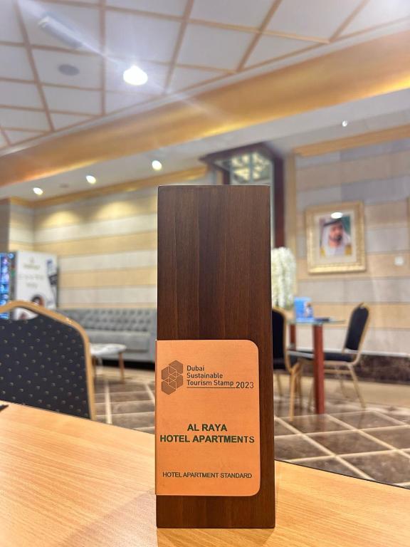 a sign sitting on top of a wooden table at Al Raya Hotel Apartments in Dubai