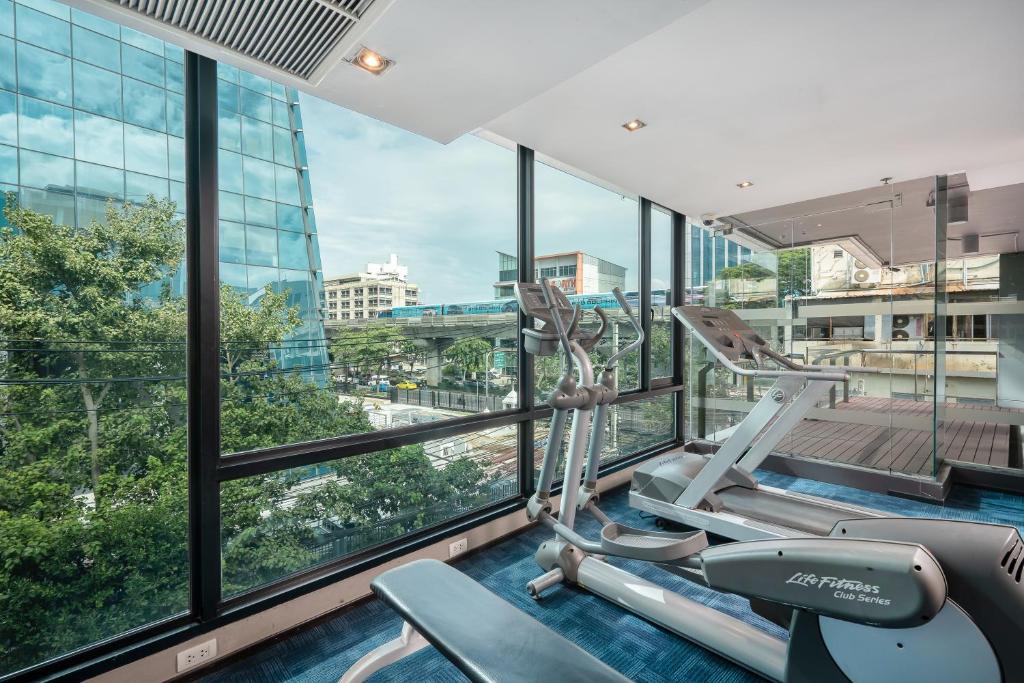 A windowed fitness room with elliptical machines and a city outlook.