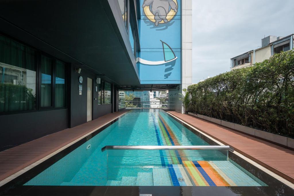 A narrow lap pool with a colorful striped floor and shaded deck.