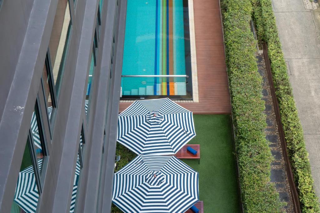 A rooftop pool beside striped umbrellas and a narrow strip of artificial lawn.