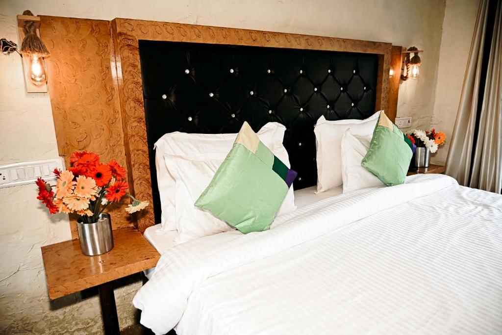 1 cama grande con sábanas blancas y almohadas verdes en Corbett Tiger Retreat en Rāmnagar
