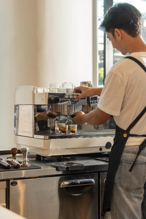 A staff member prepares espresso at a commercial coffee station.