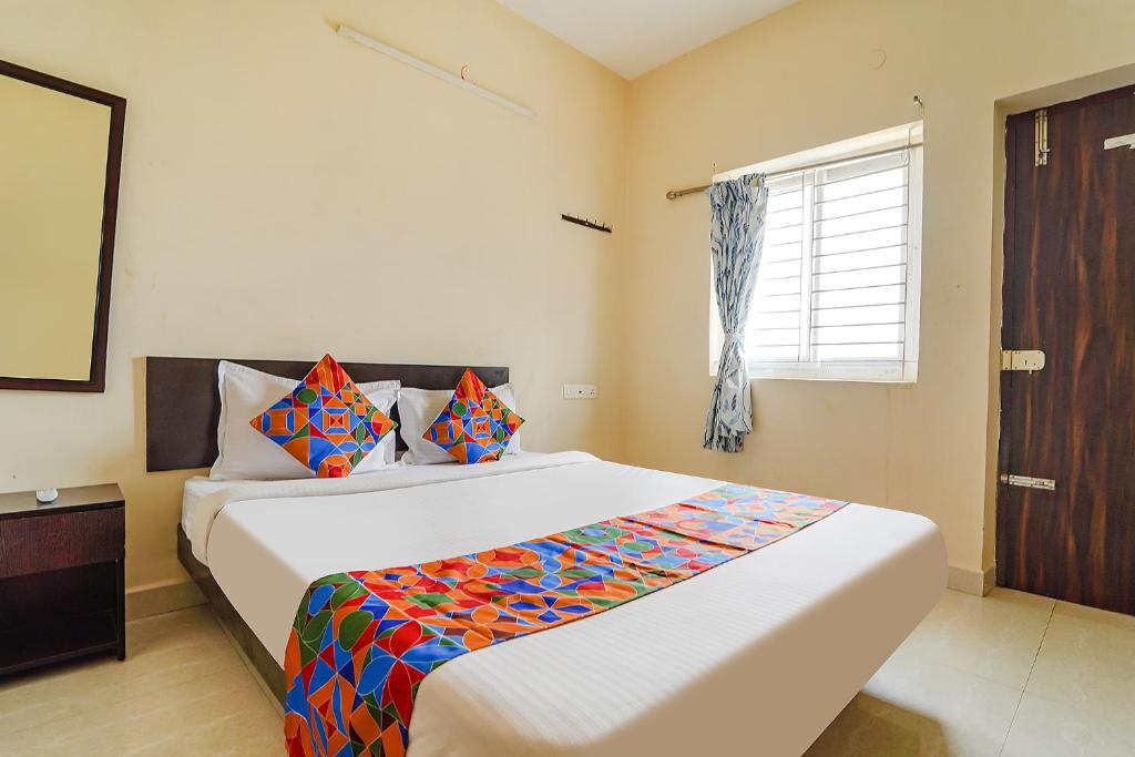 sypialnia z dużym białym łóżkiem z kolorową pościelą w obiekcie FabExpress Vangal Nest w mieście Pīlamedu