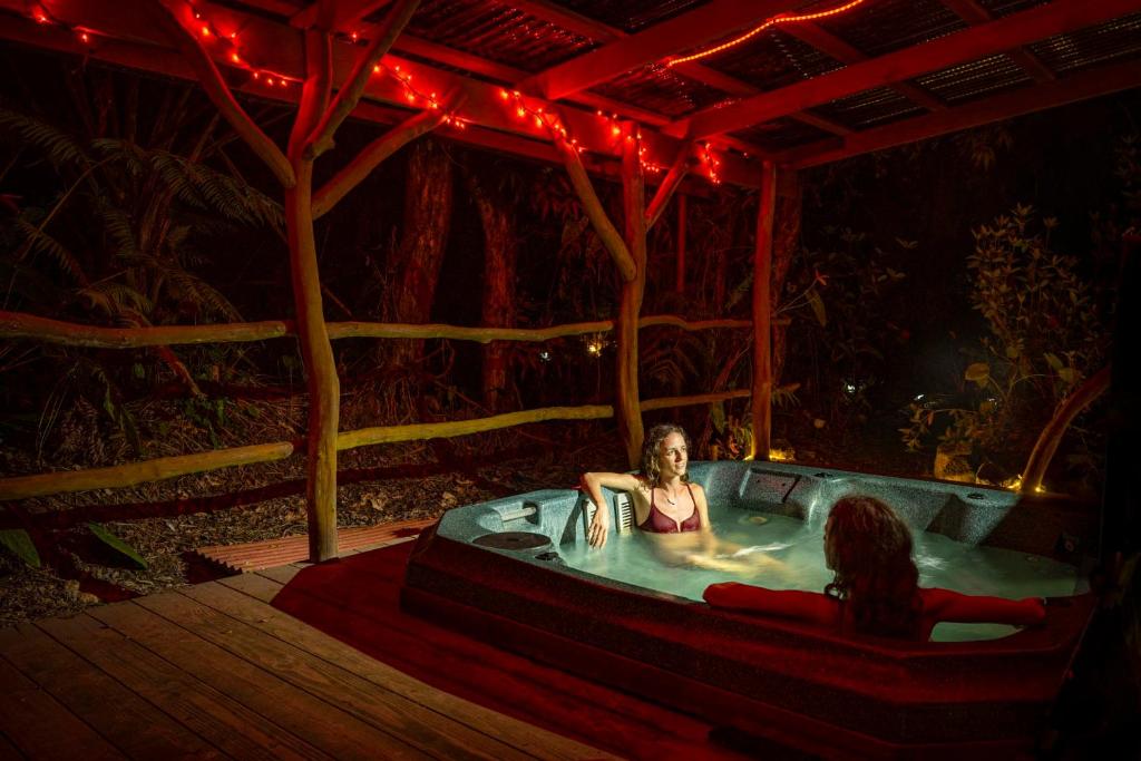 zwei Frauen sitzen in einer Whirlpool-Badewanne im Wald in der Unterkunft Volcano Inn Bed n Breakfast in Volcano