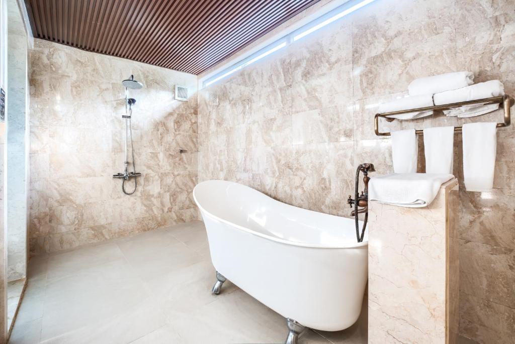 A spacious marble-look bathroom with a freestanding clawfoot tub and open shower.