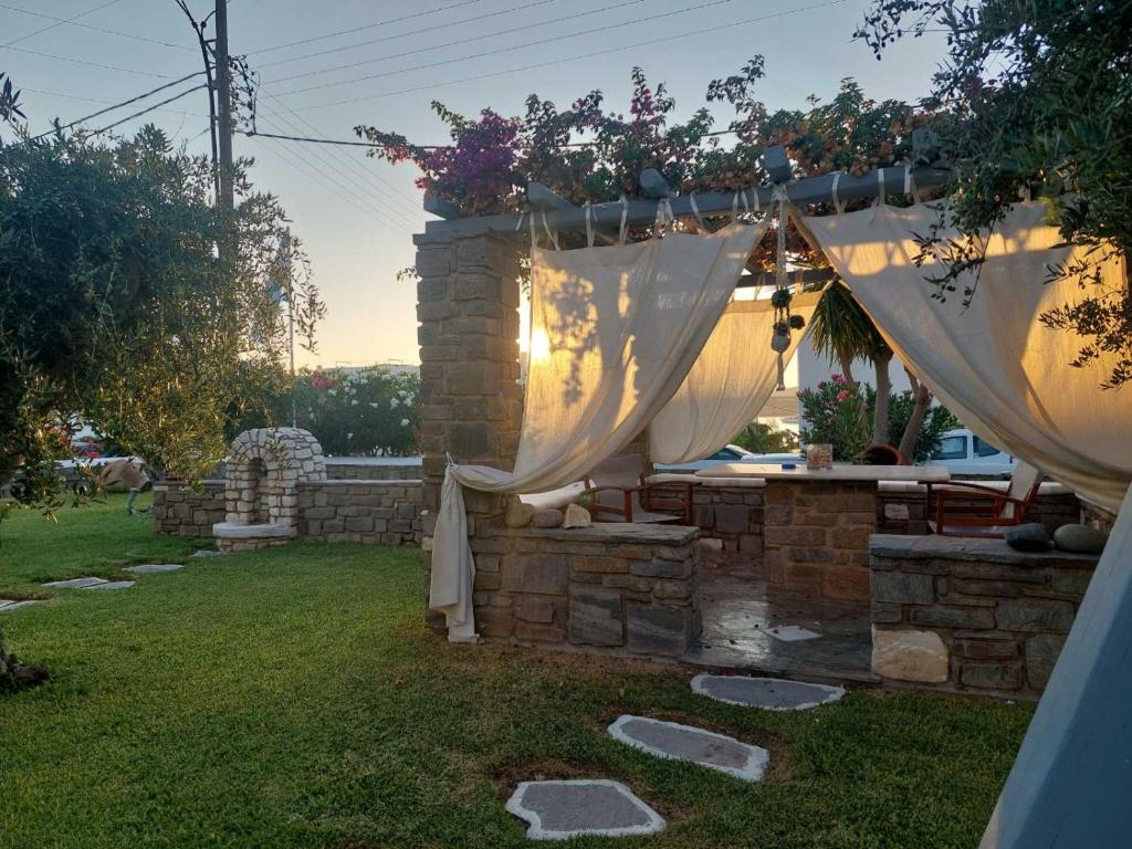 a backyard with a stone wall with a white curtain at Pension Sofia in Parikia