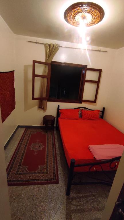 1 dormitorio con cama roja y TV de pantalla plana en Residence Gharnata app 11 imm I en Marrakech