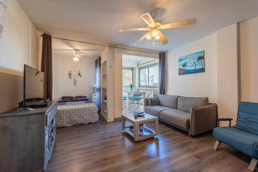 un salon avec un canapé et un ventilateur de plafond dans l'établissement La Petite Vague - Appt à moins d'un km de la plage, à La Grande Motte