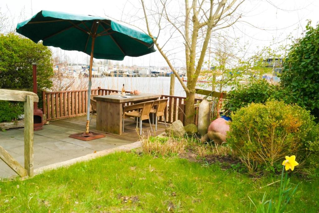 a patio with a table and an umbrella at Bijzonder chalet An der Marina met sauna in Anjum