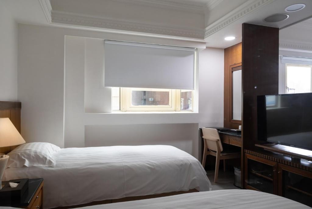 a hotel room with two beds and a flat screen tv at Hub Hotel Kaohsiung Cisian Branch in Kaohsiung