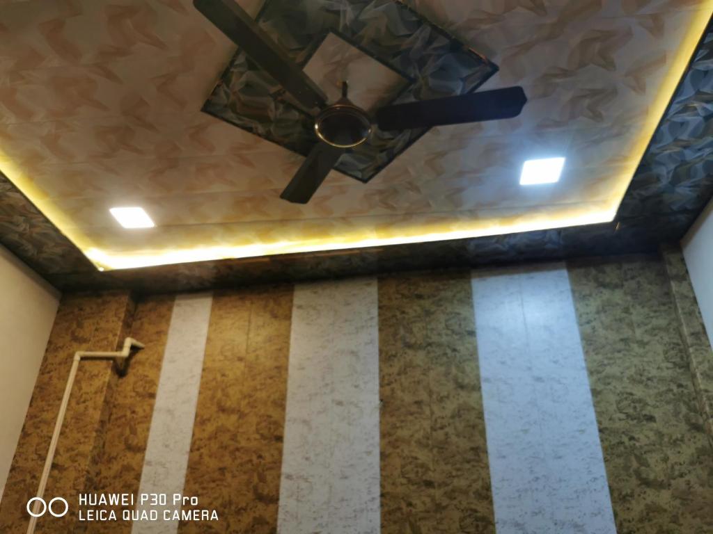 ventilatore a soffitto in camera con pavimento a righe di Kadiya dharamshala a Mathura
