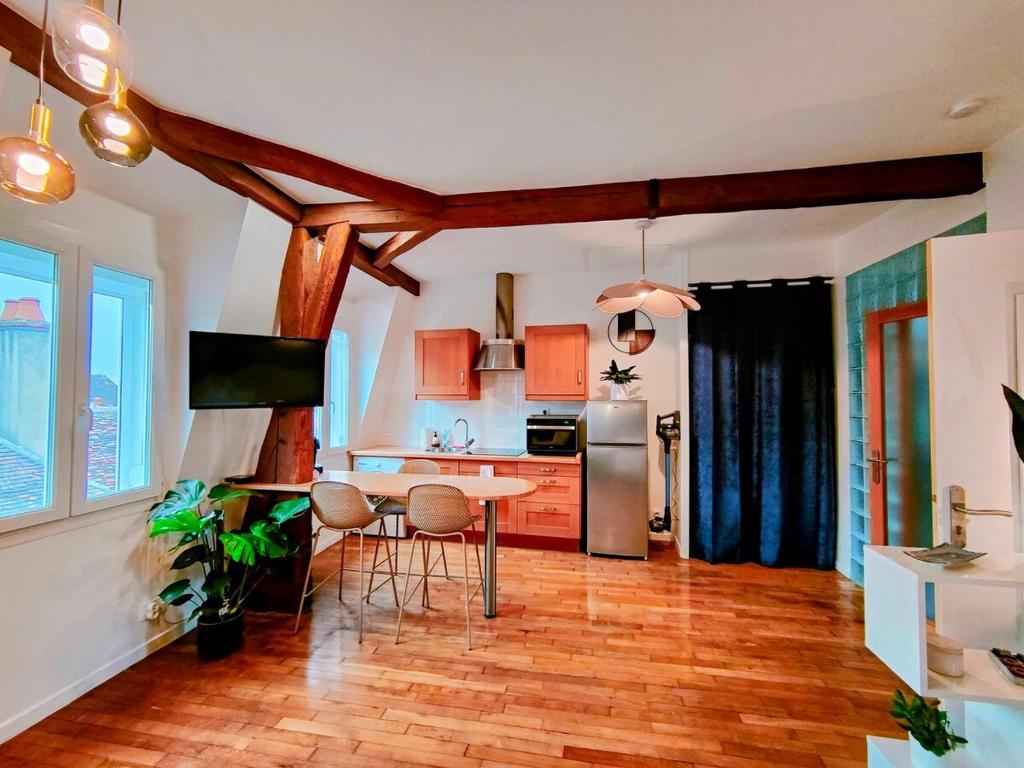 une cuisine avec une table et un réfrigérateur dans l'établissement Toit & Bois - Séjour à Auxerre, à Auxerre