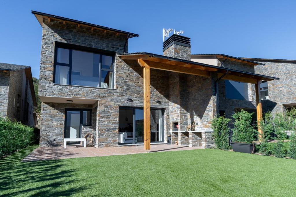 a stone house with a patio and grass at Casa rural de lujo en Alt Urgell, Pirineos. in Aravell