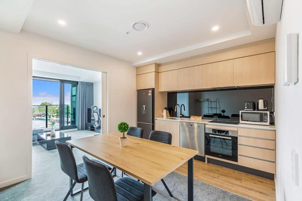 a kitchen and dining room with a wooden table and chairs at Cozy apartment by Eden Park in Auckland