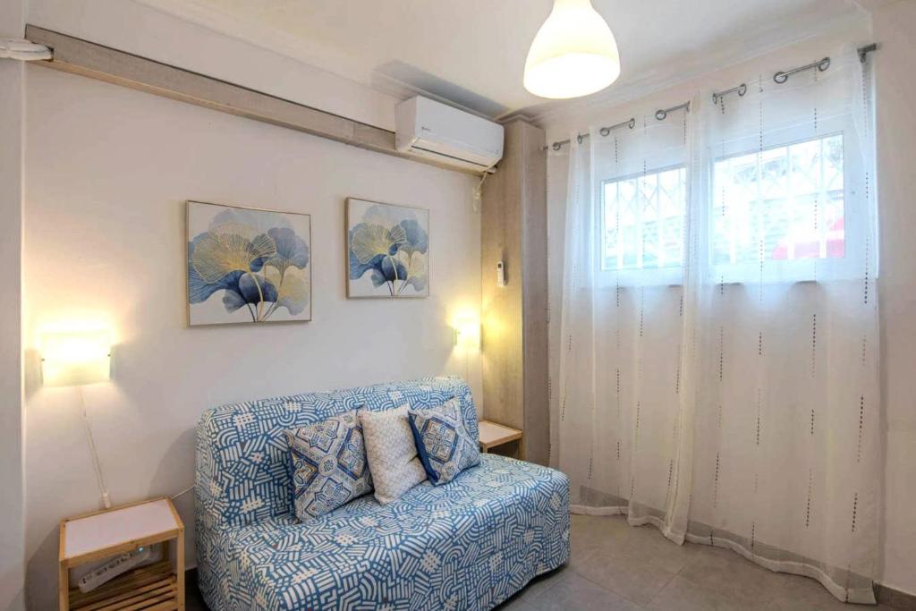 sala de estar con silla azul y ventana en Your perfect choice in Athen's best location, en Atenas