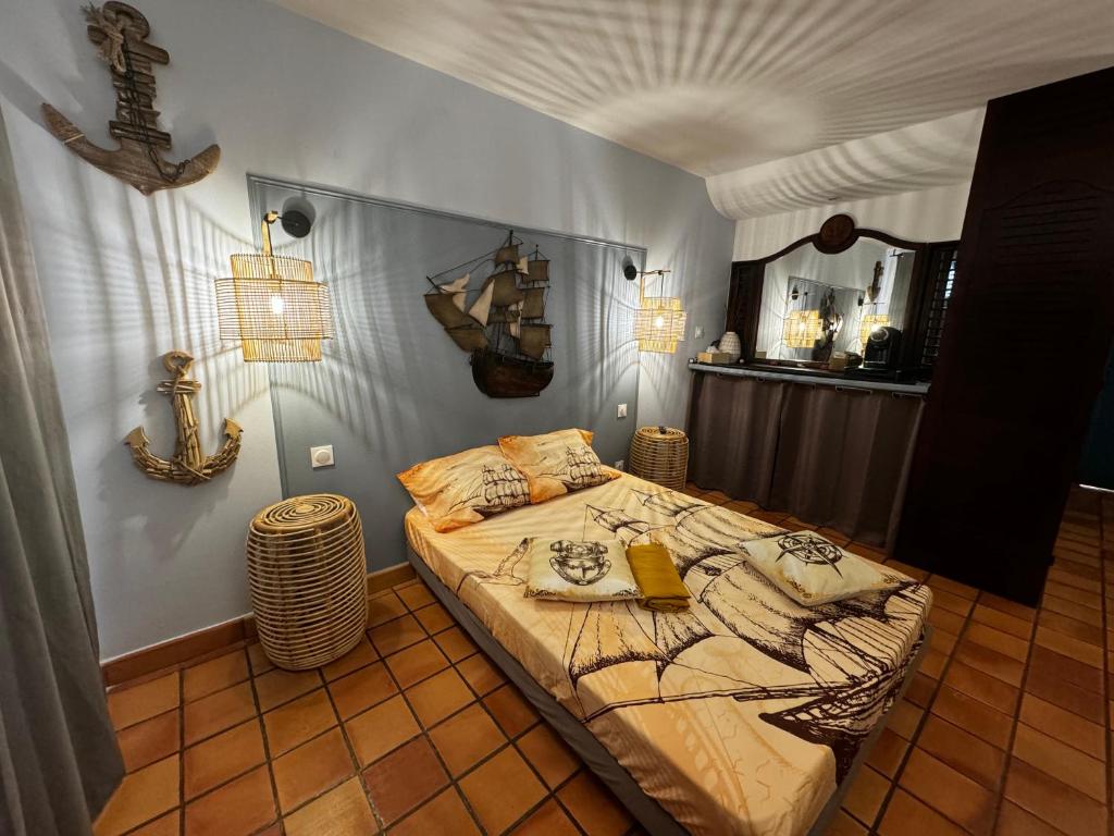 1 dormitorio con cama y espejo en la pared en La Caravelle - Agréable studio vue sur mer avec piscine en La Trinité