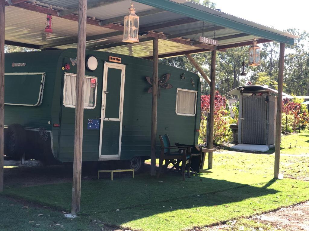 a green trailer with awning and a table under it at BERTHA caravan River Heads in River Heads