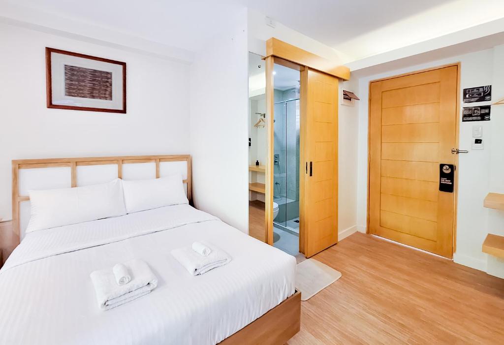 een slaapkamer met een wit bed en een houten deur bij Areca Boracay Bed & Breakfast in Boracay