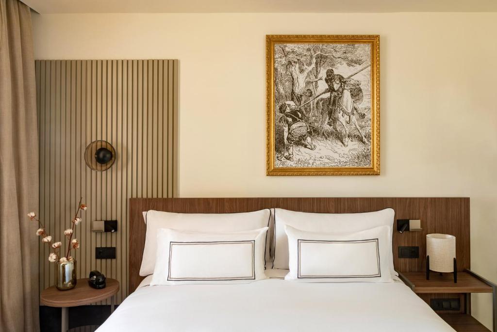 a bed with two pillows and a painting on the wall at Casa de las Artes, member of Meliá Collection in Madrid