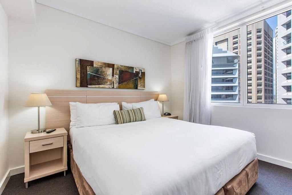 una camera bianca con un grande letto e una finestra di Brisbane Casino Tower Luxury Suites a Brisbane