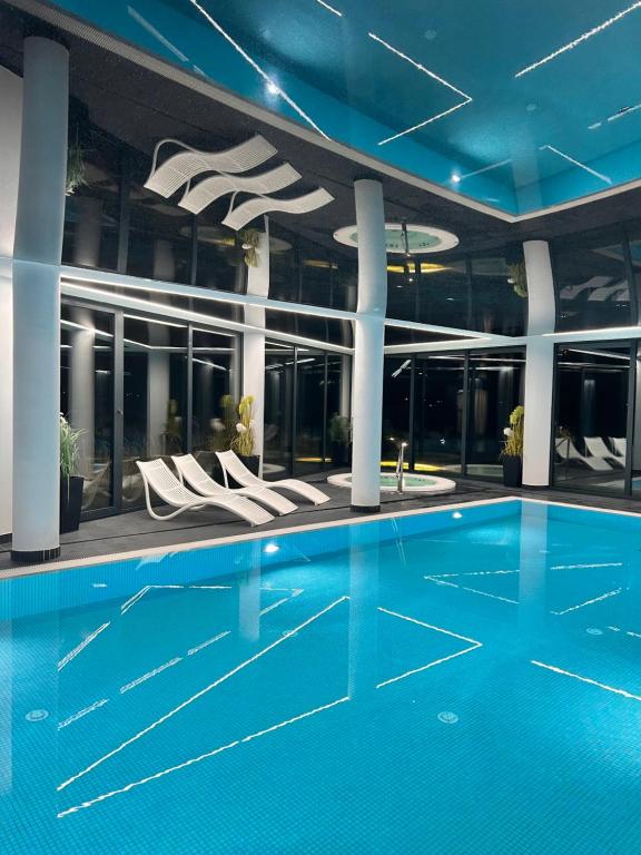 a swimming pool in a building with white chairs at Westin House Resort Kołobrzeg Apartament DELUX in Kołobrzeg