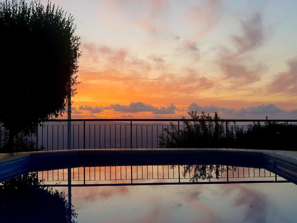 een weerspiegeling van een zonsondergang in een zwembad bij Ithaki House in Lyso