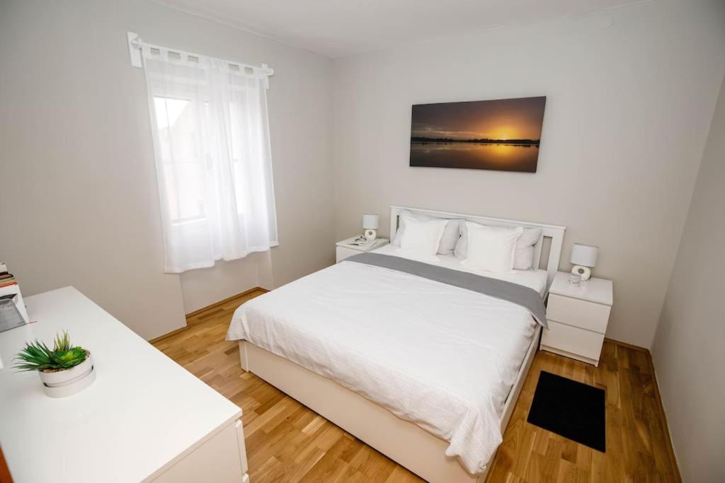 a bedroom with a white bed and two white tables at Apartment Old Town - Bambo in Knin