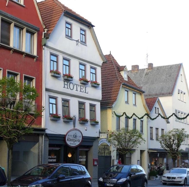 un hotel en una calle de la ciudad con coches aparcados delante en Hotel Café Rhönperle en Bad Neustadt an der Saale