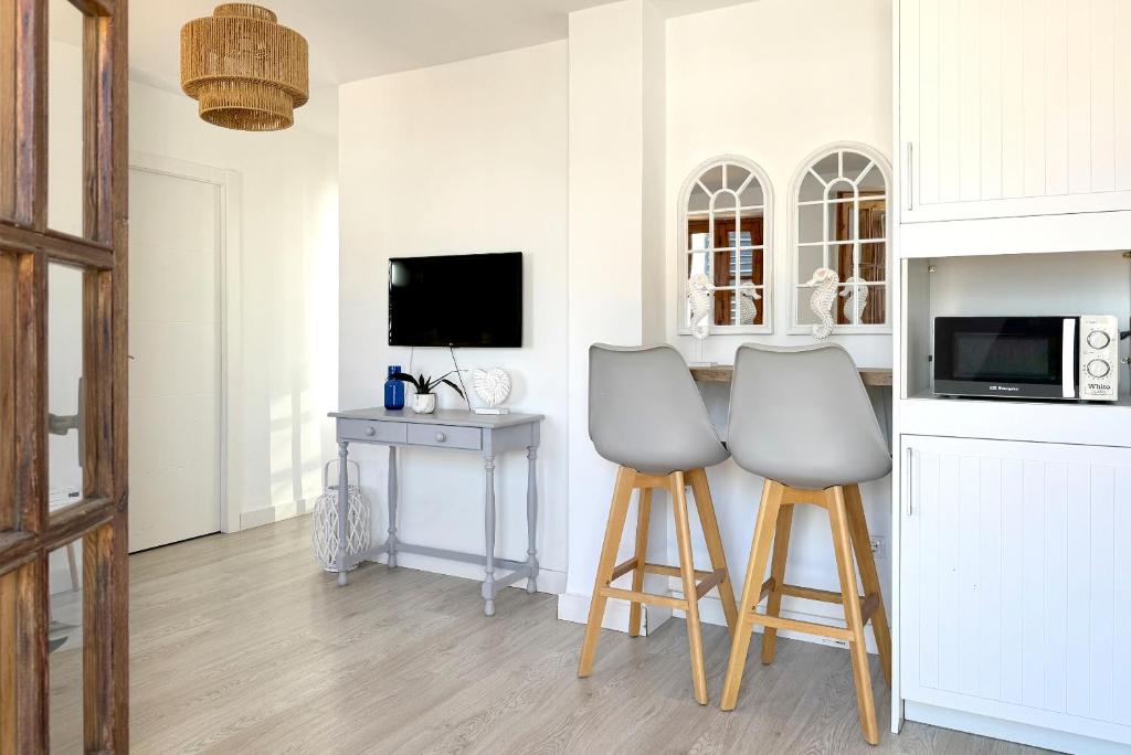 a kitchen with two stools and a table with a tv at Apartamentos Vela Blanca in San José