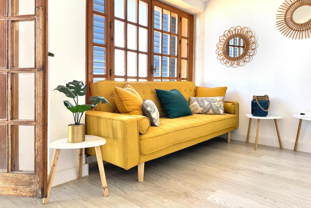 a yellow couch in a living room with pillows on it at Apartamentos Vela Blanca in San José