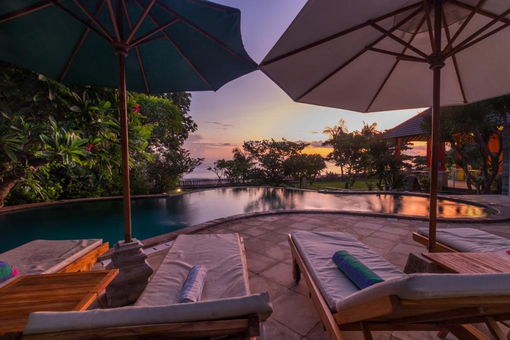 einen Pool mit Sonnenschirmen und Liegestühlen neben einem Pool in der Unterkunft Villa Sky Dancer - Bali in Amed