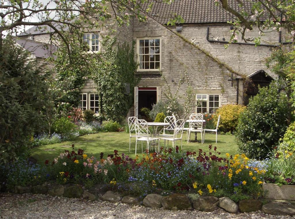 a garden with chairs and flowers in front of a house at Bramwood Guest House in Pickering