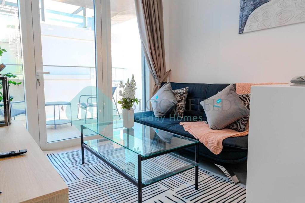 ein Wohnzimmer mit einem blauen Sofa und einem Glastisch in der Unterkunft Deluxe 1bedroom In Oasis 2 in Al Qurayyah