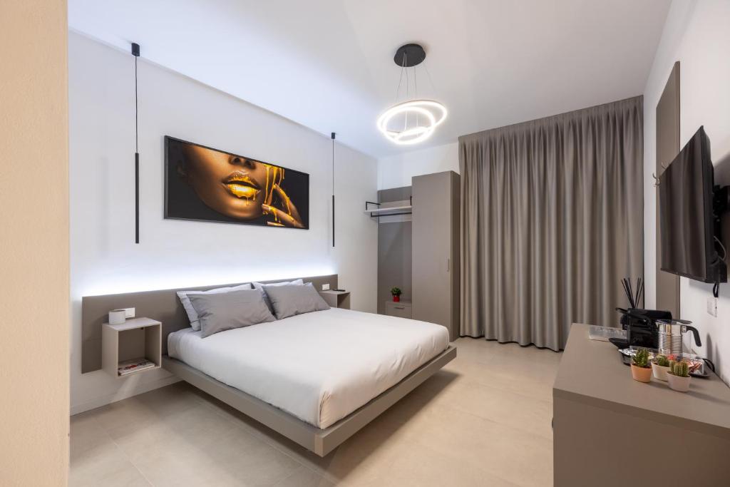 een witte slaapkamer met een bed en een televisie bij Luxury Station Suite in Bologna