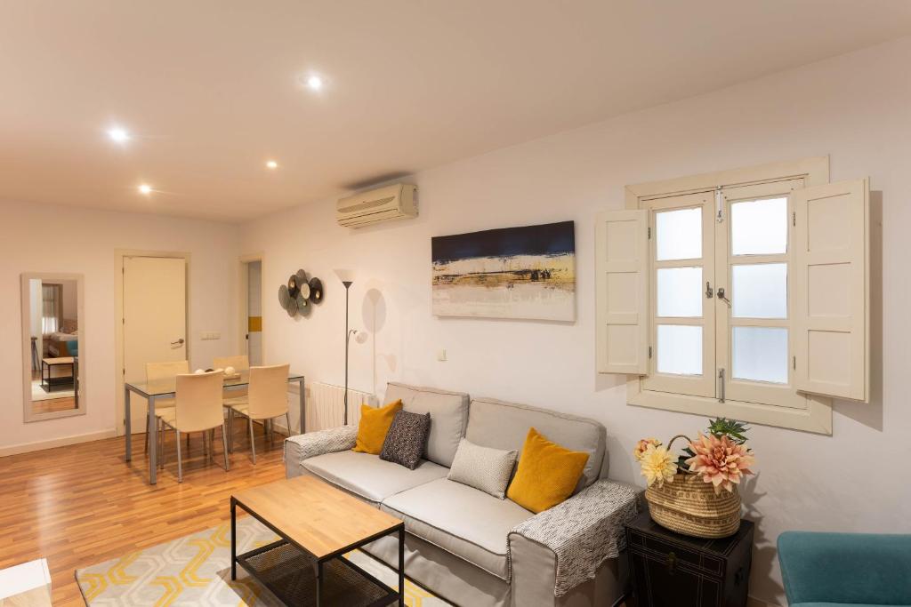 ein Wohnzimmer mit einem Sofa und einem Tisch in der Unterkunft Vidrio Urban Apartment in Sevilla