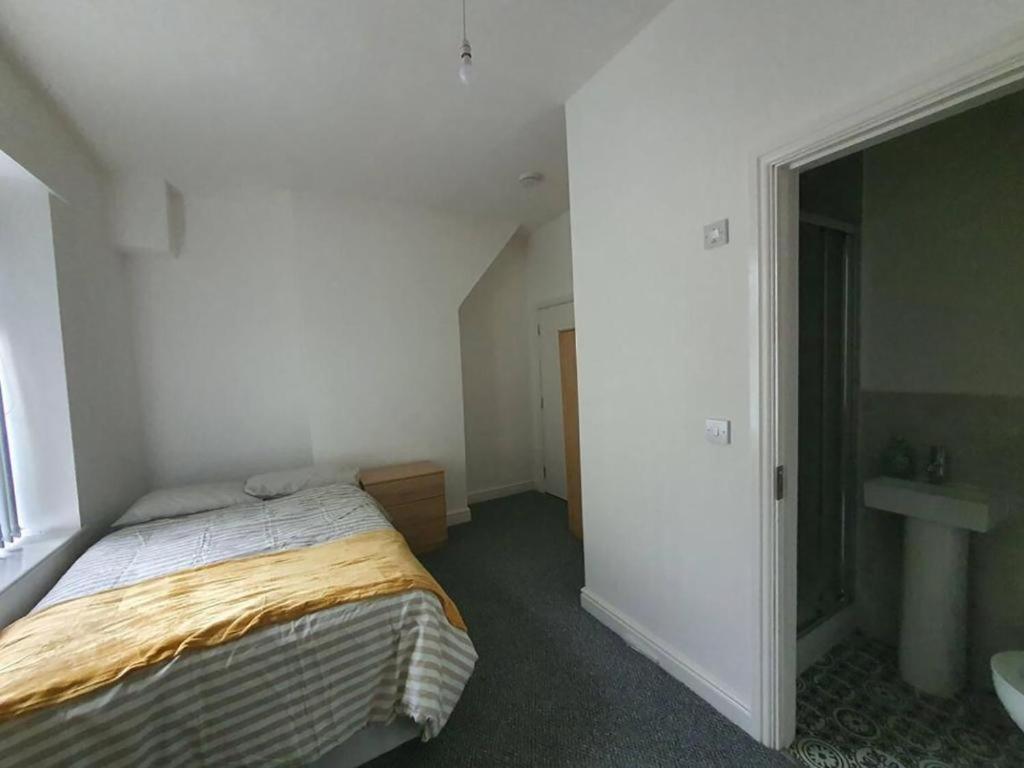 um pequeno quarto com uma cama e um lavatório em Ensuite Double-bed L3 Burnley City Centre em Burnley