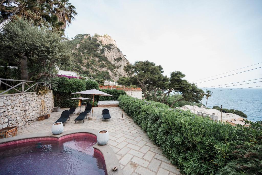 uma piscina com cadeiras e um guarda-sol junto ao oceano em Villa Michika by Elite Villas em Capri