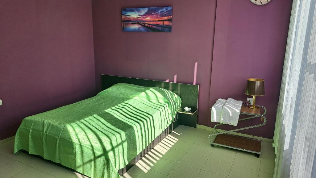 um quarto com uma cama verde e paredes roxas em LS Park Apartment em Ruse