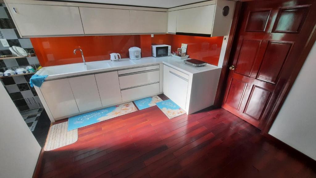 una pequeña cocina con armarios blancos y una puerta roja en Homestay Lucas's House, en Liên Trì (3)