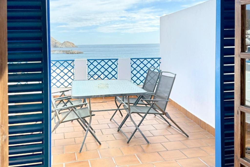 a balcony with a table and chairs and the ocean at Apartamentos Vela Blanca in San José
