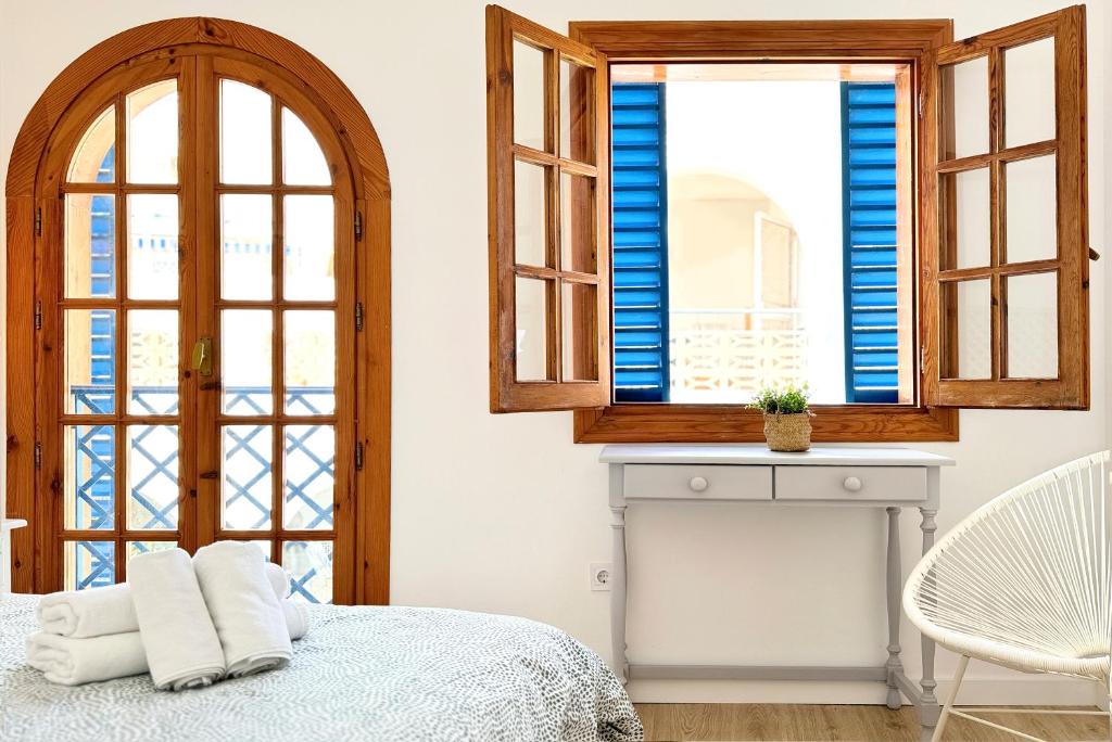 a bedroom with blue shuttered windows and a bed at Apartamentos Vela Blanca in San José