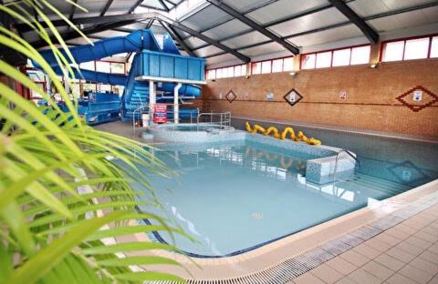 uma grande piscina interior com um escorrega aquático em Poppy 44 em Ferndown